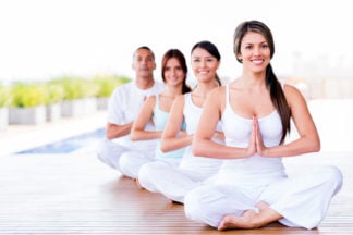 Group of people doing yoga exercises and smiling